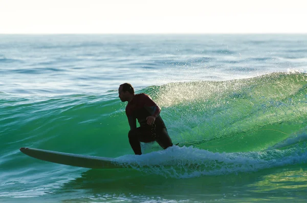 Larga tabla surfeando las olas al atardecer — Foto de Stock