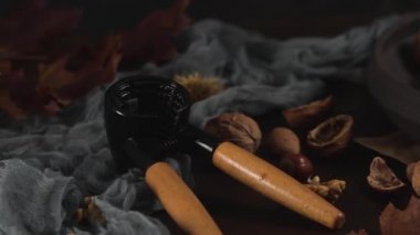 Fındıkkıran aleti ve siyah seramik tabağıyla sonbahar kuru meyveleri masada..