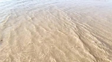 Deniz dalgaları sahile yavaş çekimde kum sıçrıyor. Kumlu sahil kıyısında yakın su yüzeyi. Manzaralı manzara okyanus su dalgalarını sakinleştirir.