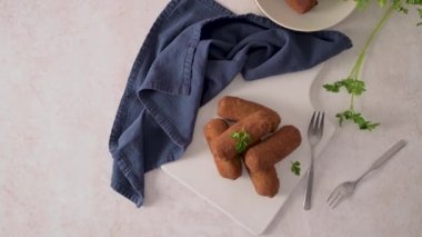 Et kroketleri ve maydanoz yaprakları mutfak tezgahındaki beyaz seramik tabaklarda..