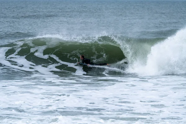 Bodyboarder performing a tube trick surfing ocean wavesurfing ocean wave on a cloudy winter day.