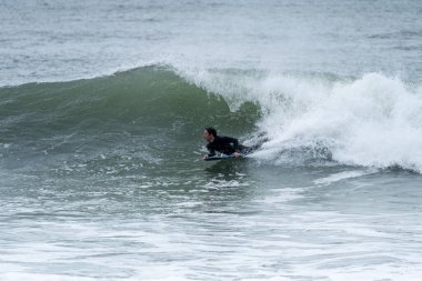 Bulutlu bir kış gününde sörf yapan sörfçü..