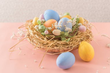 Pembe arka planda yuvada paskalya yumurtaları.