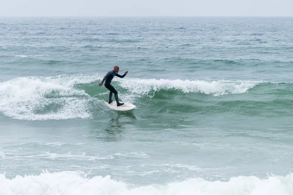 Portekiz, Furadouro plajında sörf tahtası ile sörf yapan bir sörfçü. Okyanusta dalgaları yakalayan adamlar. Su sörfü sporu.
