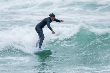 Sörfçü kız Furadouro sahilinde yumuşak bir sörf tahtası ile sörf yapıyor, Ovar - Portekiz.