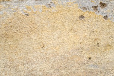 Beyaz taş duvarda sarı boya kırılıyor..