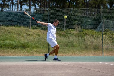 Tenisçi sahada raketle ters vuruş yapıyor..