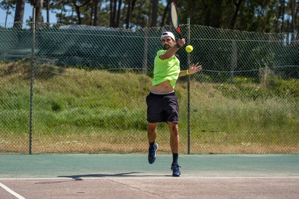 Tennis player hitting forehand at ball with racket on court.