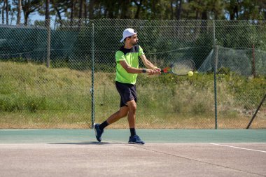 Tenisçi sahada raketle ters vuruş yapıyor..