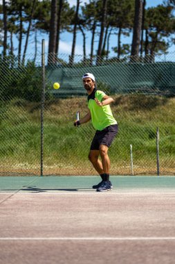 Tenis oyuncusu sahada raketle forehand vuruyor..