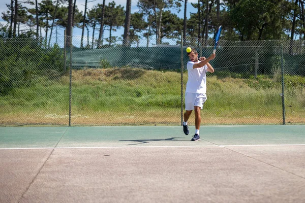 Tenis oyuncusu sahada raketle forehand vuruyor..