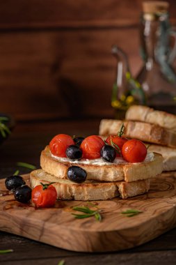 Krem peynirli taze bruschetta, siyah zeytin ve vişneli domates yakından..
