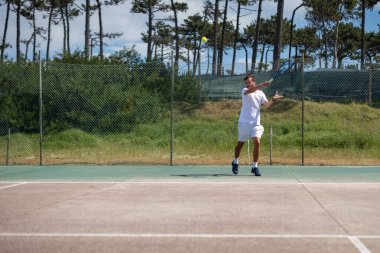 Tenis oyuncusu sahada raketle forehand vuruyor..