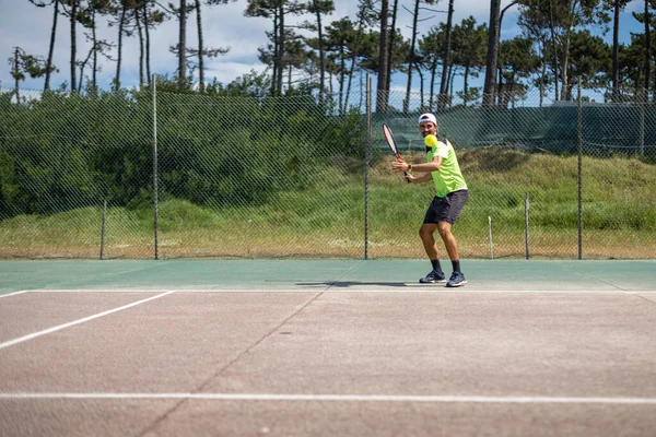 Tenis oyuncusu sahada raketle forehand vuruyor..