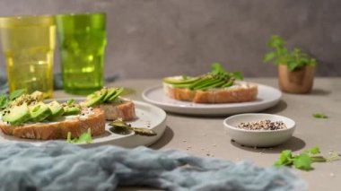 Avokado krem peynirli sağlıklı tost ve tabakta buğday ekmeği. Lezzetli atıştırmalıklar ve avokado sandviçleri. Yemek kompozisyonu, lezzetli İtalyan yemeği..