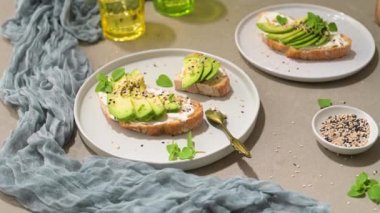Avokado krem peynirli sağlıklı tost ve tabakta buğday ekmeği. Lezzetli atıştırmalıklar ve avokado sandviçleri. Yemek kompozisyonu, lezzetli İtalyan yemeği..