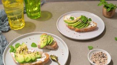 Avokado krem peynirli sağlıklı tost ve tabakta buğday ekmeği. Lezzetli atıştırmalıklar ve avokado sandviçleri. Yemek kompozisyonu, lezzetli İtalyan yemeği..