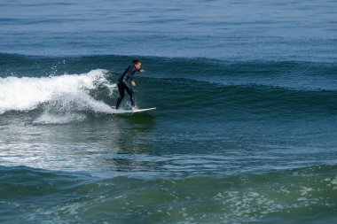 Sıcak ve güneşli bir günde sörf yapan sörfçü kız Furadouro plajında, Ovar - Portekiz.