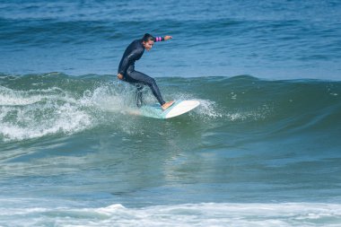 Sıcak ve güneşli bir günde sörf yapan sörfçü kız Furadouro plajında, Ovar - Portekiz.