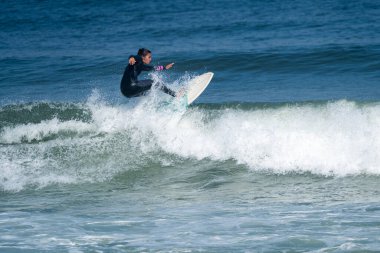 Sıcak ve güneşli bir günde sörf yapan sörfçü kız Furadouro plajında, Ovar - Portekiz.
