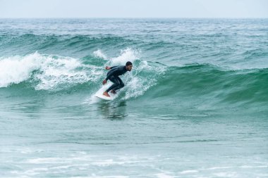 Sörfçü sisli bir sabahta sörf yapıyor Furadouro sahilinde, Ovar - Portekiz.