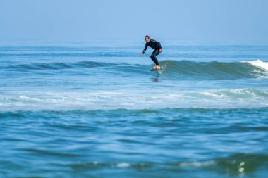 Parlak güneşli bir günde denizde sörf yapan orta yaşlı bir adam.