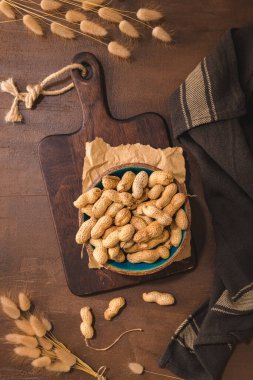 Peanuts in a ceramic bowl on a rustic kitchen countertop.