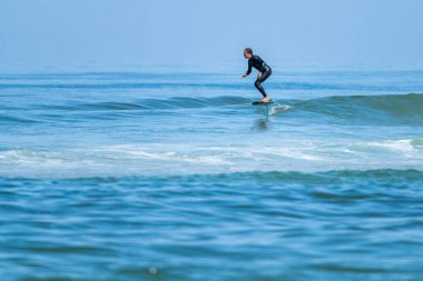 Parlak güneşli bir günde denizde sörf yapan orta yaşlı bir adam.