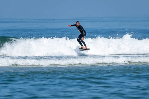 一个中年男子在阳光明媚的一天在海里冲浪或水翼冲浪 — 图库照片