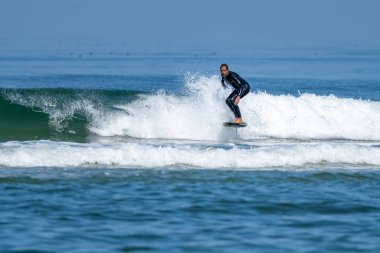 Parlak güneşli bir günde denizde sörf yapan orta yaşlı bir adam.