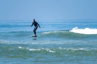 Parlak güneşli bir günde denizde sörf yapan orta yaşlı bir adam.