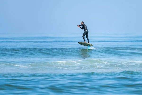 一个中年男子在阳光明媚的一天在海里冲浪或水翼冲浪 — 图库照片