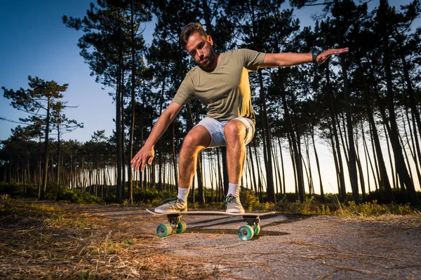 Surf skater performing a slide by the pine forest at sunset in Maceda, Ovar - Portugal.