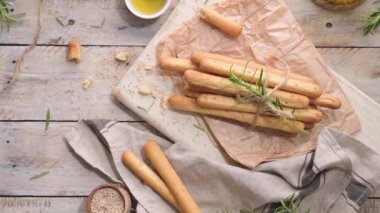 Traditional italian breadsticks grissini with rosemary, olive oil and sesame seeds on wooden countertop.