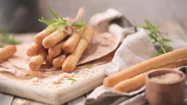 Traditional italian breadsticks grissini with rosemary, olive oil and sesame seeds on wooden countertop.