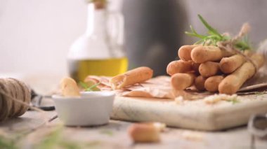 Traditional italian breadsticks grissini with rosemary, olive oil and sesame seeds on wooden countertop.