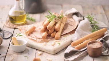 Traditional italian breadsticks grissini with rosemary, olive oil and sesame seeds on wooden countertop.