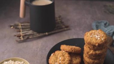 Homemade oatmeal raisin cookies with cup of cappuccino on rustic background.
