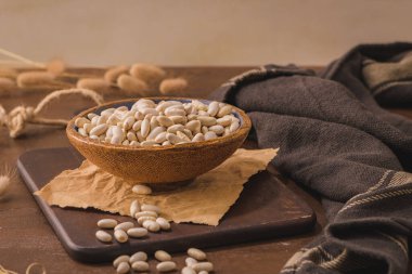 White beans in a ceramic bowl on a rustic kitchen countertop.