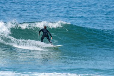 Portekiz 'in Furadouro plajında sörf yapan sörfçü. Okyanusta dalgaları yakalayan adamlar. Su sörfü sporu.