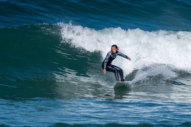 Sıcak ve güneşli bir günde sörf yapan sörfçü kız Furadouro plajında, Ovar - Portekiz.