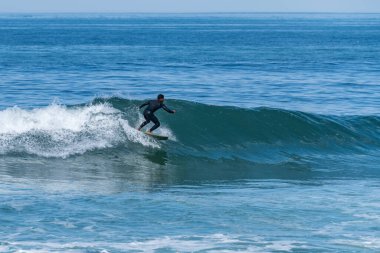 Portekiz 'in Furadouro plajında sörf yapan sörfçü. Okyanusta dalgaları yakalayan adamlar. Su sörfü sporu.