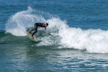 Portekiz 'in Furadouro plajında sörf yapan sörfçü. Okyanusta dalgaları yakalayan adamlar. Su sörfü sporu.