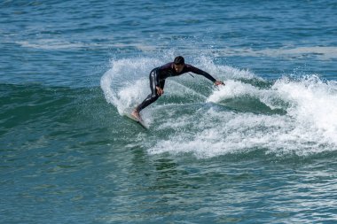 Portekiz 'in Furadouro plajında sörf yapan sörfçü. Okyanusta dalgaları yakalayan adamlar. Su sörfü sporu.