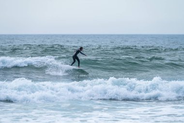 Torreira sahilinde bulutlu bir öğleden sonra sörf yapan sörfçü kız, Murtosa - Portekiz.