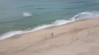 Dalgıç kıyafeti giyen sörfçüler bulutlu bir öğleden sonra deniz kenarında sörf tahtası tutuyorlar..