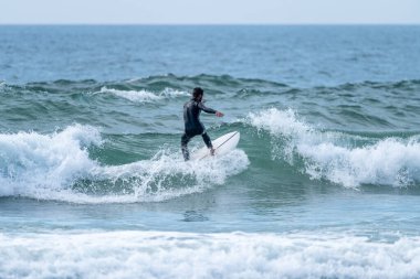 Torreira sahilinde bulutlu bir öğleden sonra sörf yapan sörfçü, Murtosa - Portekiz.