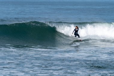 Sıcak ve güneşli bir günde sörf yapan sörfçü kız Furadouro plajında, Ovar - Portekiz.