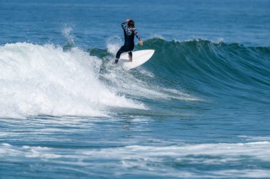 Sıcak ve güneşli bir günde sörf yapan sörfçü kız Furadouro plajında, Ovar - Portekiz.