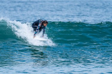 Sıcak ve güneşli bir günde sörf yapan sörfçü kız Furadouro plajında, Ovar - Portekiz.